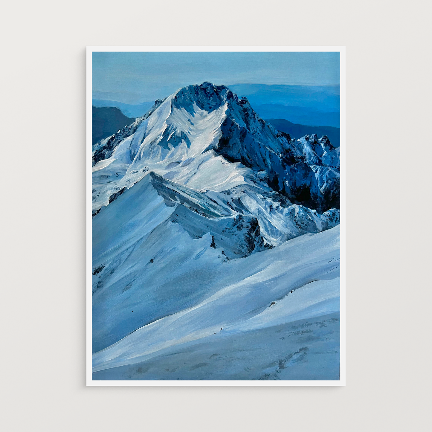 A framed painting on a white wall. 

It is a realistic acrylic landscape painting of a prominent mountain covered in snow. The predominant color is a deep blue.