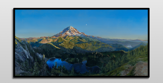 A framed painting hung on a white wall.

The painting is a vibrant realistic landscape of Mount Rainier in the summer. It overlooks Mowich Lake. The sun is setting, casting golden light on the mountain and surrounding hills. The moon can be seen faintly beyond the mountain.